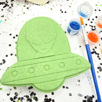 Green alien UFO paint your own bath bomb with paint containers and brushes on a white background
