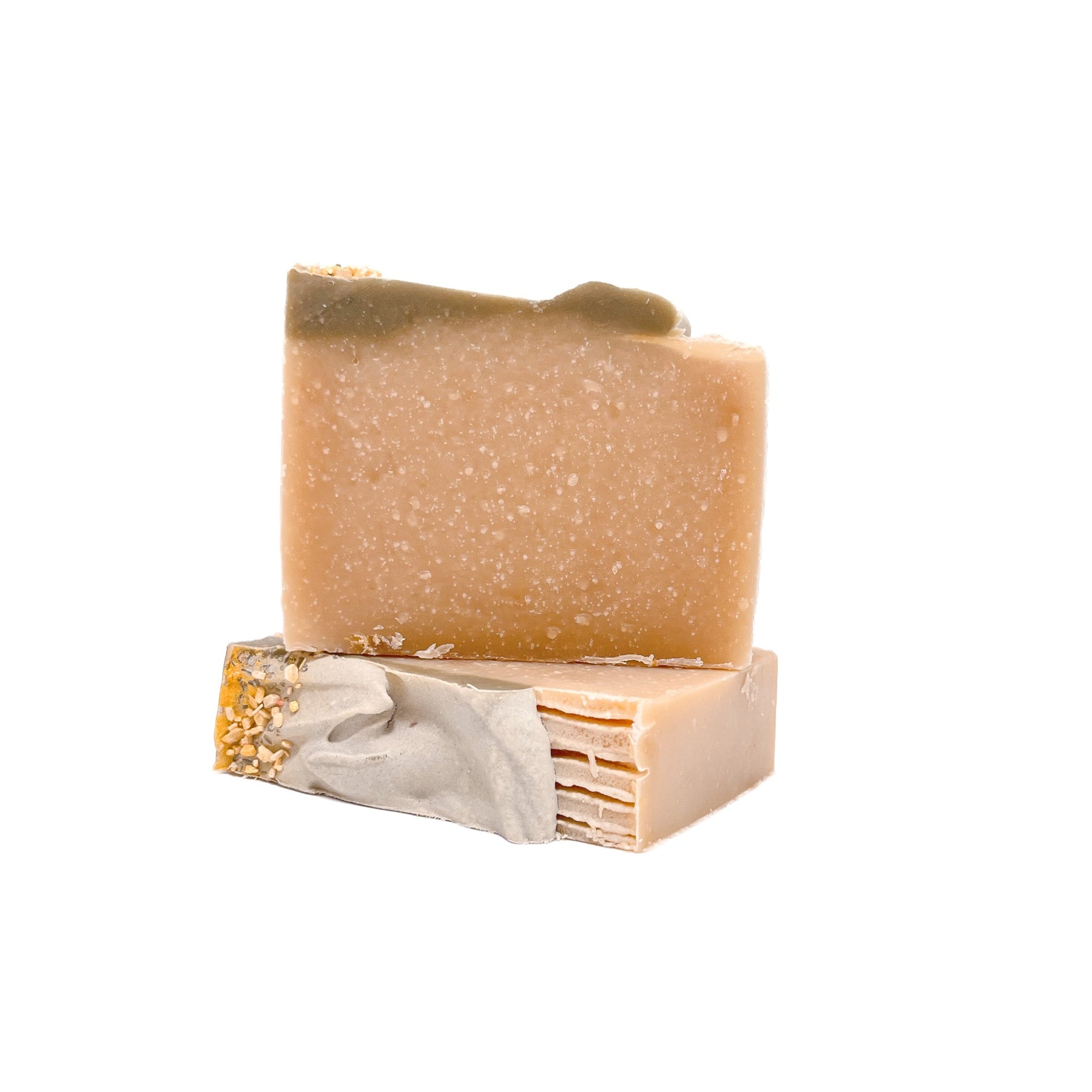 Two bars of natural colored soap with a green top. One flat and one upright. 
