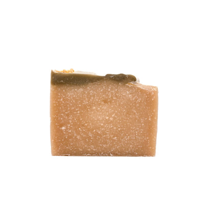 A bar of natural colored handmade soap, topped with a bit of green soap, and gold epsom salt dusted with gold mica.