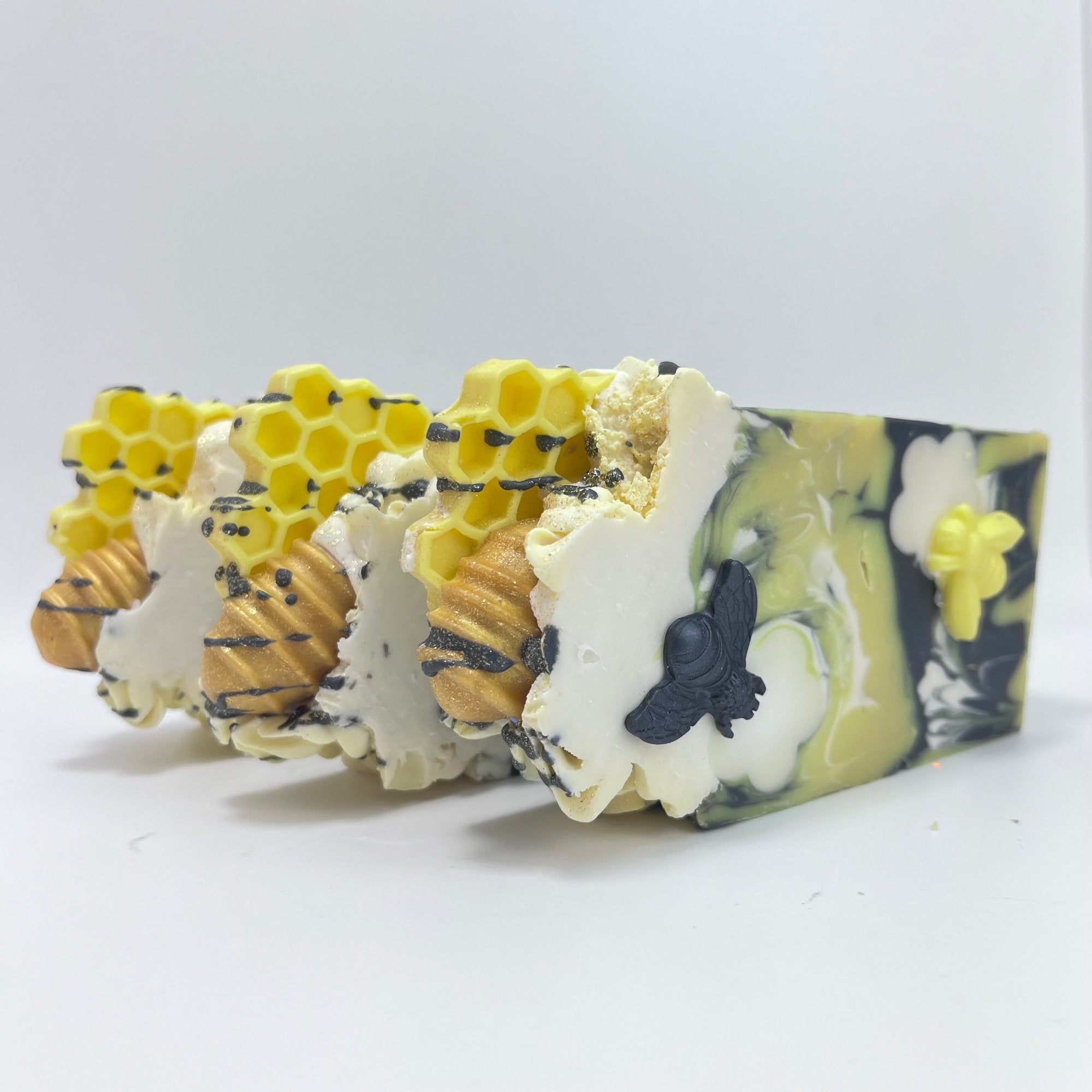 Three bars of Rusted Acre Soap Company's Bee Happy soap. Displayed showing the texture and embeds of honey comb and spoon.
