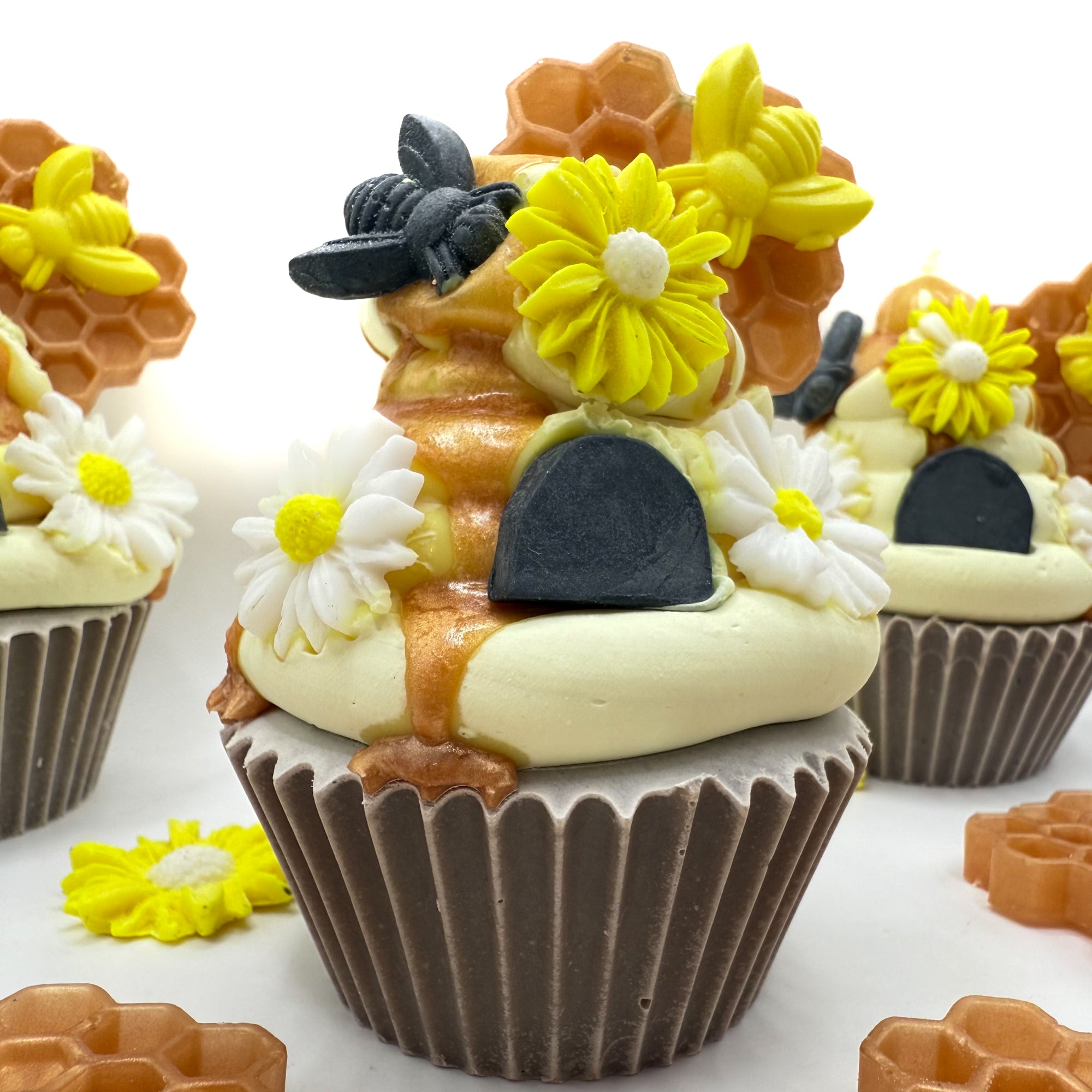 Close-up of Beehive cupcake soap with piped frosting and intricate soap embellishments: honeycomb, bees, and daisies.