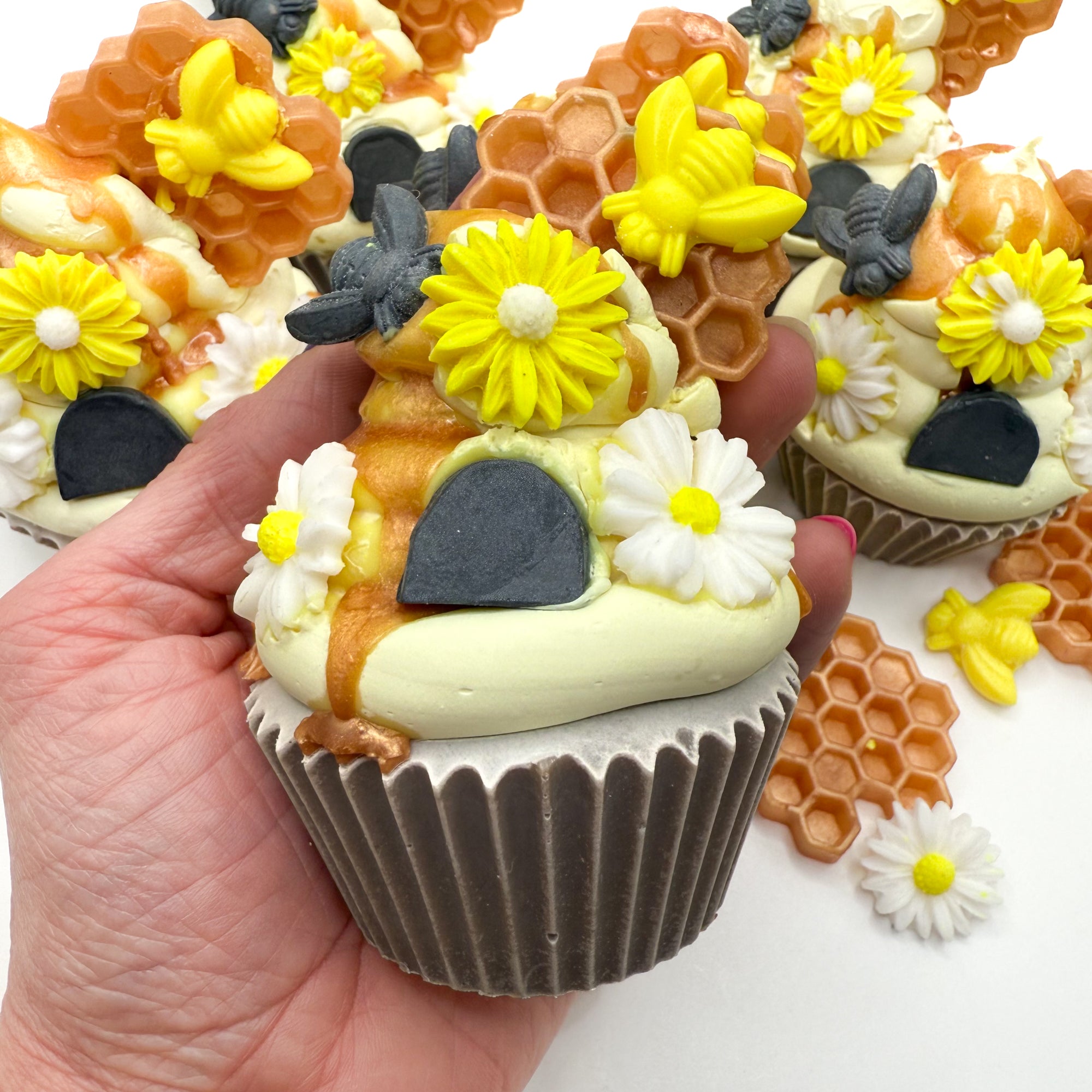Hand holding Beehive cupcake soap showing detailed soap embellishments of honeycomb, bees, and piped floral designs