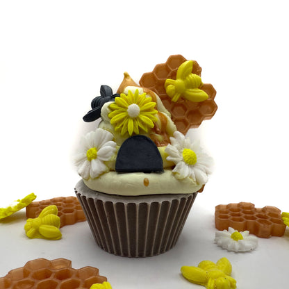 A handmade beehive cupcake soap with a dark brown base yellow hand-piped top looks like a hive with white and yellow soap flowers, black and yellow bees.