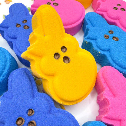 Multiple bitten bunny bath bombs with multiple colors, one yellow one sitting upright. 