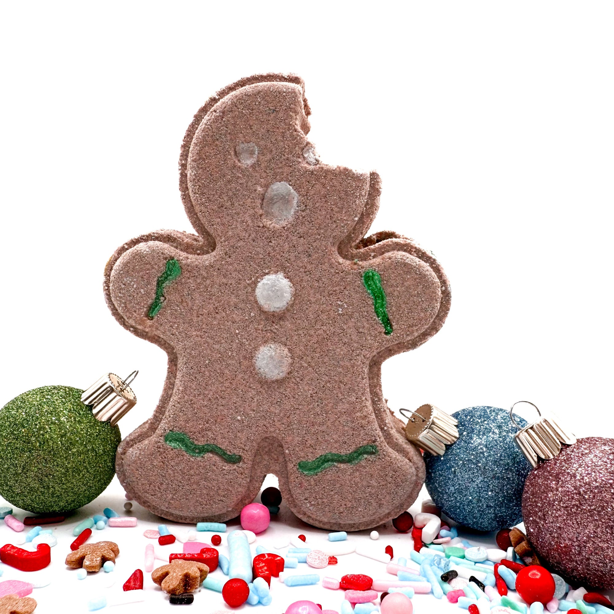 Decorative gingerbread man bath bomb hand made by Rusted Acre Soap Co  with Christmas ornaments and sprinkles on a white background