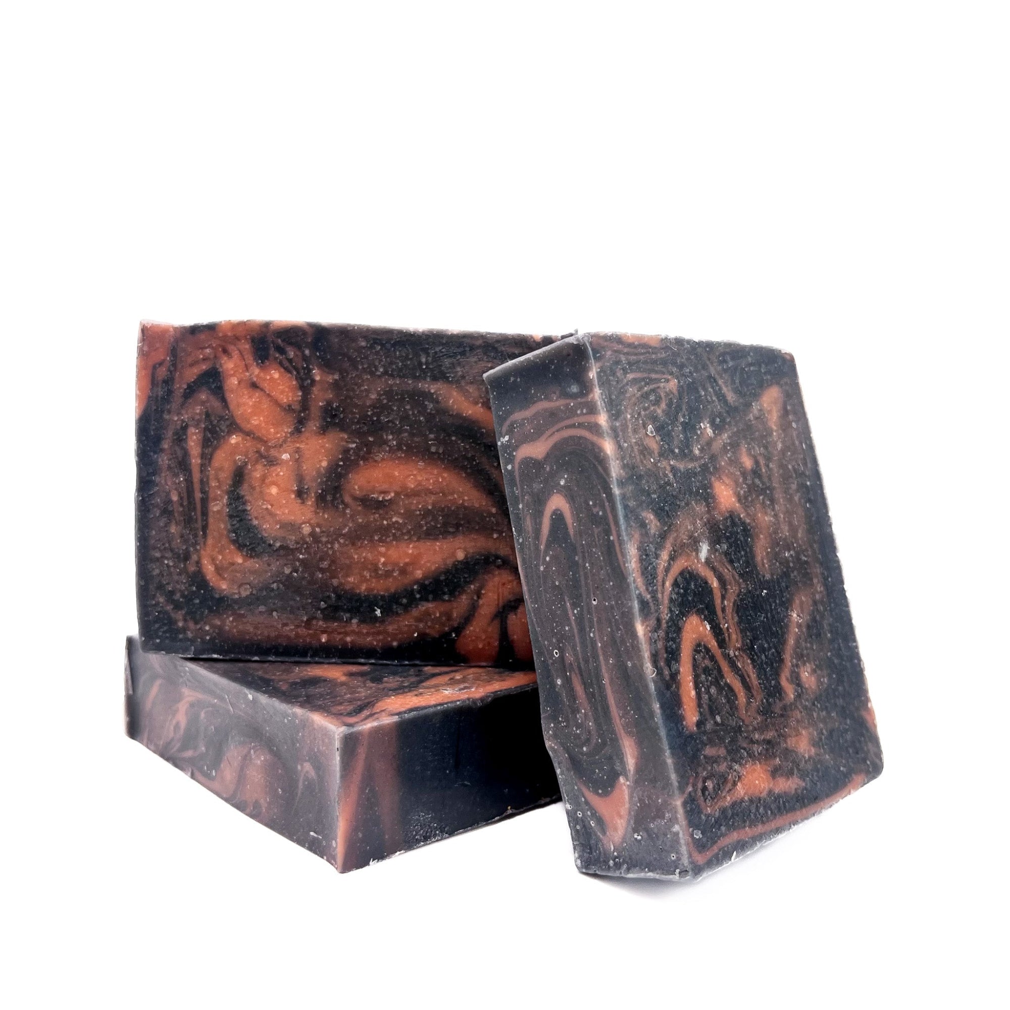 Three bars of Rusted Acre Soap Company's black Cherry handmade soap swirled charcoal black and red.