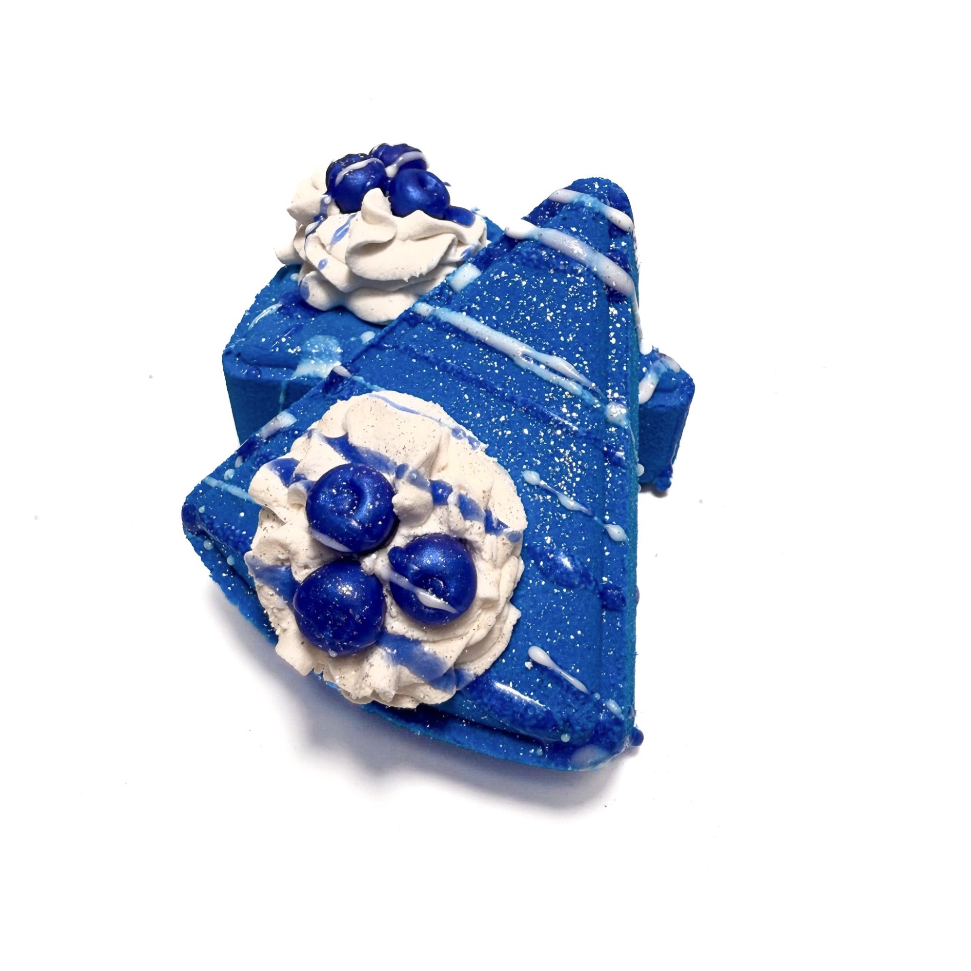 Two slices of Rusted Acre Soap Companies blue berry pie bath bombs topped with soap blueberries and bubble bath frosting. 