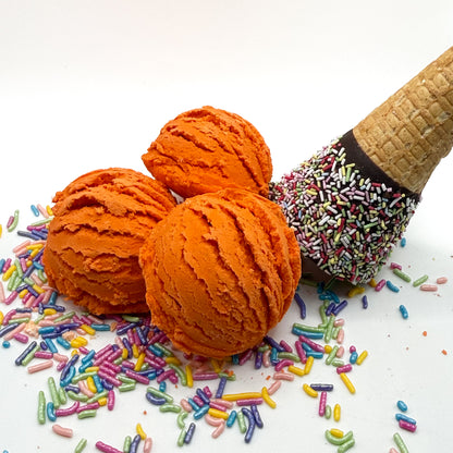 Three orange pumpkin spice scented bubble bath scoops handmade by Rusted Acre Soap Co. Scoop looks like an ice cream scoop. White background with sprinkles and ice cream cone prop on a white background. 