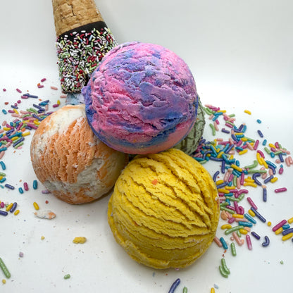 Multiple bubble bath scoops handmade by Rusted Acre Soap Co. Scoop looks like an ice cream scoop. White background with sprinkles and ice cream cone prop on a white background. 