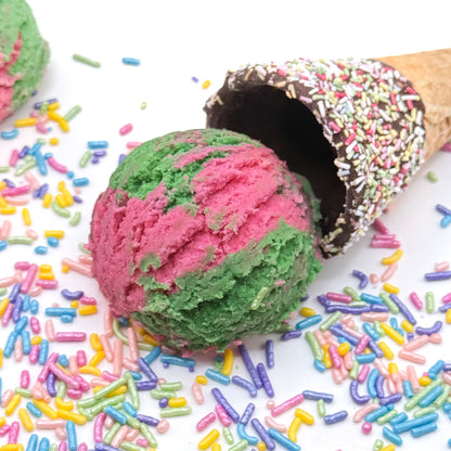 Pink and green watermelon bubble bath scoop shaped like ice cream surrounded by sprinkles on a white background!