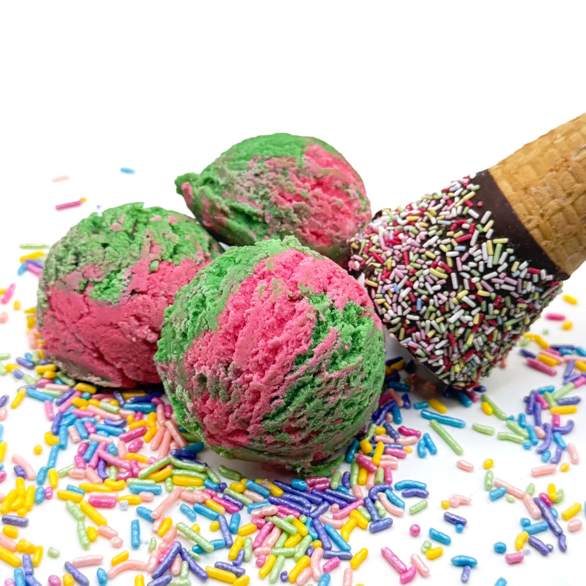 Three pink and green ice cream scoop shaped watermelon bubble bath in a waffle cone prop with colorful sprinkles on a white background.