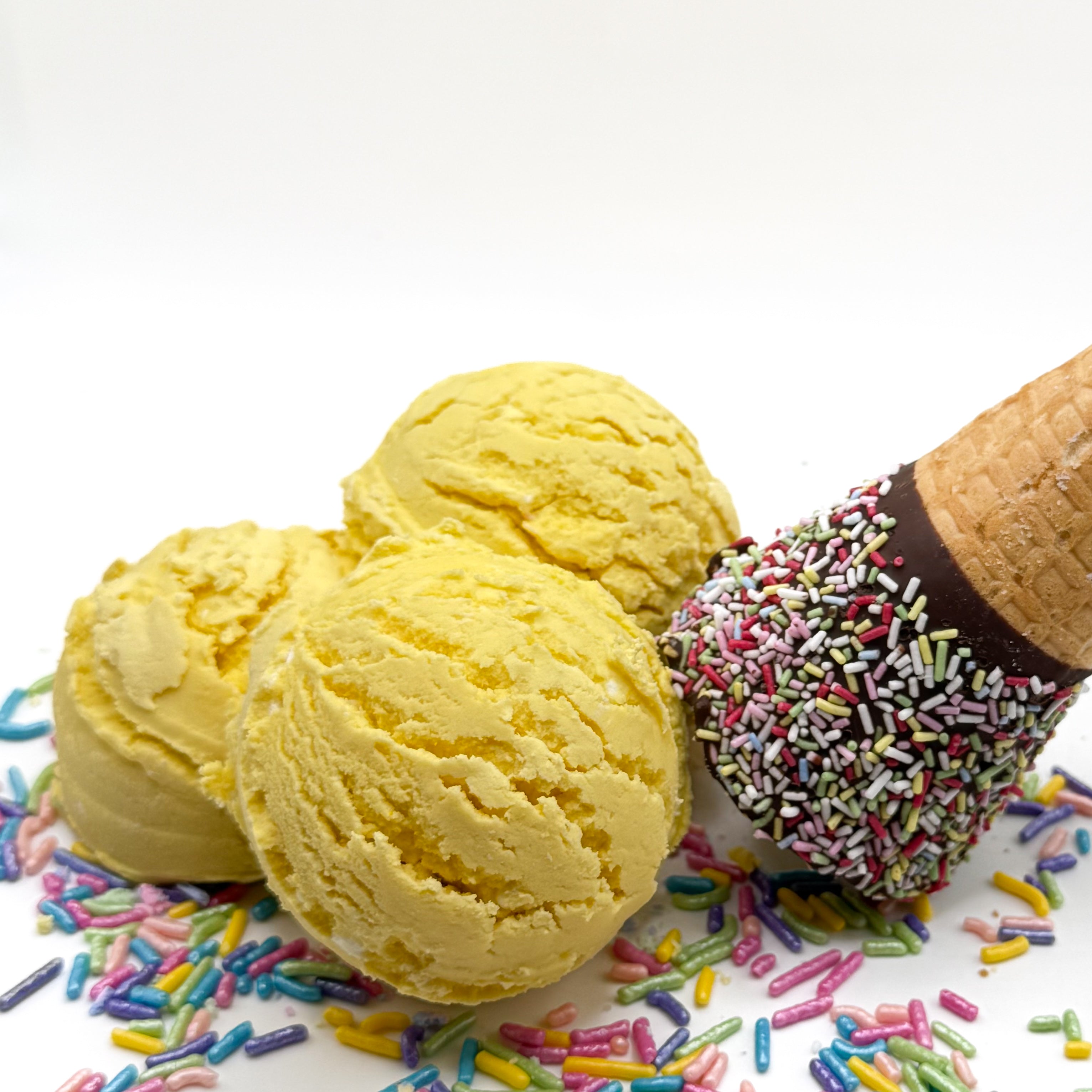 Three yellow lemon cupcake scented bubble bath scoops that look like scoops of ice cream on a white background with sprinkles and an ice cream cone 