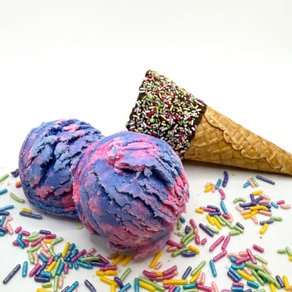 Two Raspberry Vanilla bubble bath scoops handmade by Rusted Acre Soap Co. Scoops look like pink and purple ice cream scoops with sprinkles and ice cream cone prop on a white background. 