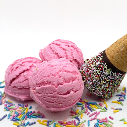 Three pink strawberries and cream scented bubble bath scoops that look like scoops of ice cream on a white background with sprinkles and an ice cream cone.