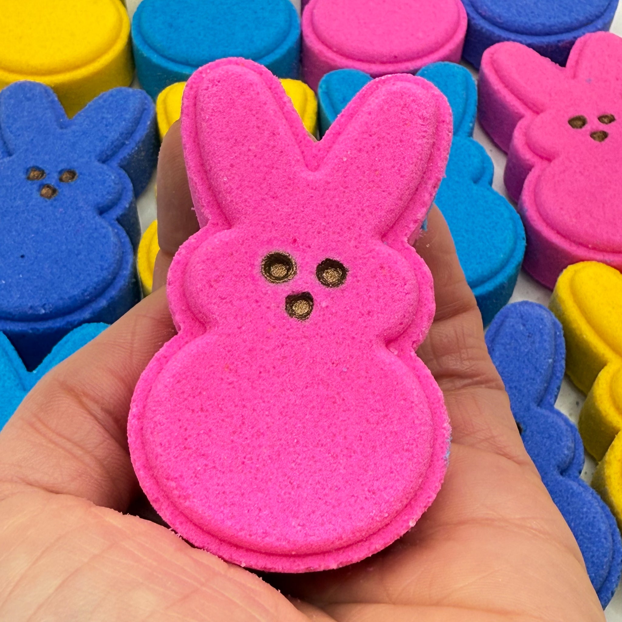 A handmade pink bunny bath bomb from Rusted Acre Soap Co. Hand-painted brown eyes.