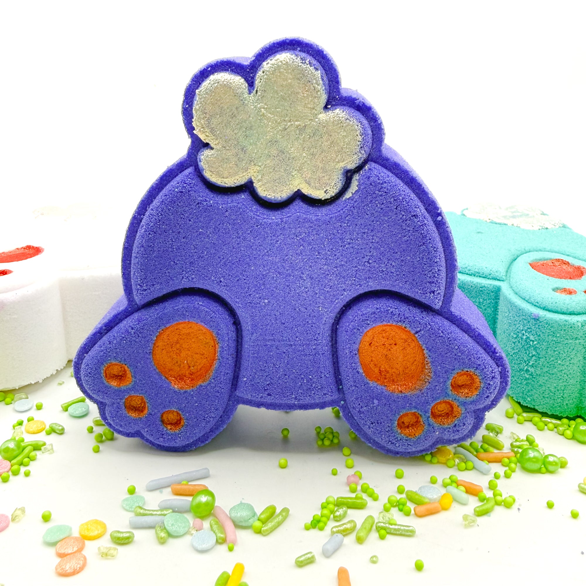 Hand painted purple bunny butt bath bomb with pink feet pads, sparkly tail on a blue background with Easter sprinkles. 