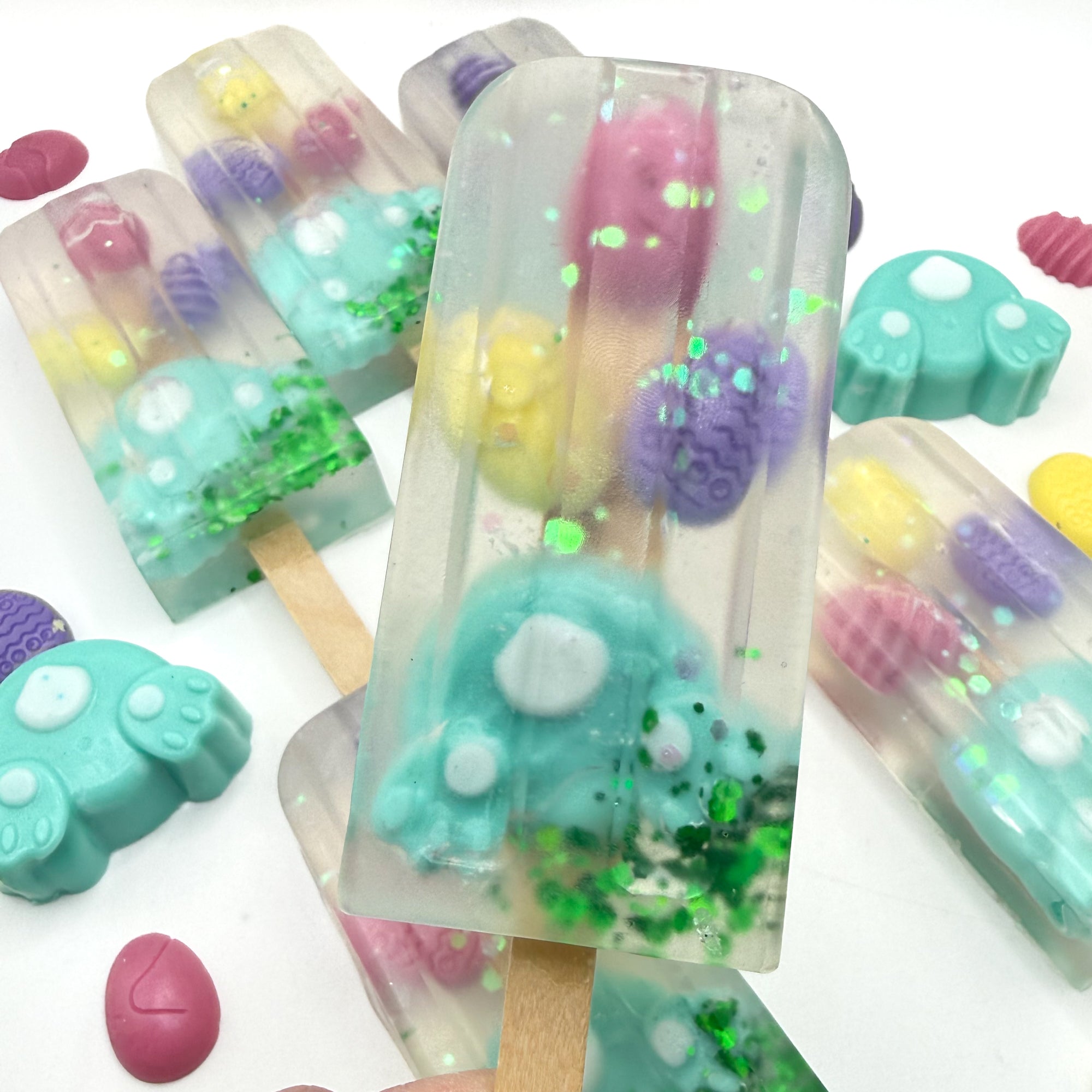 Colorful Easter popsicle shaped soap bars with bunny and egg soap embedded inside on a white background