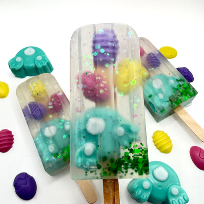 Colorful Easter popsicle shaped soap bars with bunny and egg soap embedded inside on a white background. Handmade by Rusted Acre Soap Co.