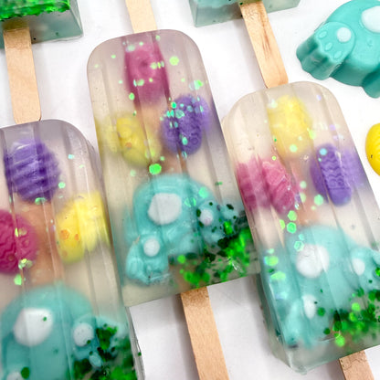 Easter popsicle shaped soap bars with bunny and egg soap embedded inside on a white background. Handmade by Rusted Acre Soap Co.