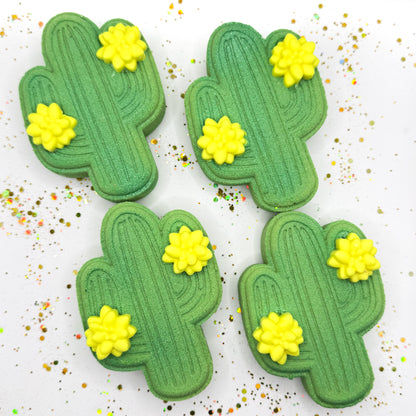 Four green cactus shaped bath bombs with yellow flowers on a white background. 