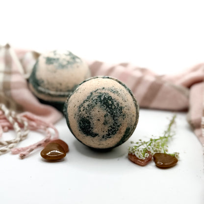 Two brown and tan cashmere bath bombs on a white background with props. 