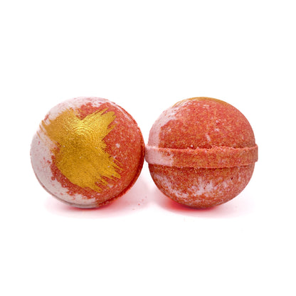 Two red and white swirled round bath bombs hand-painted gold streaks on the tops from Rusted Acre Soap Co.