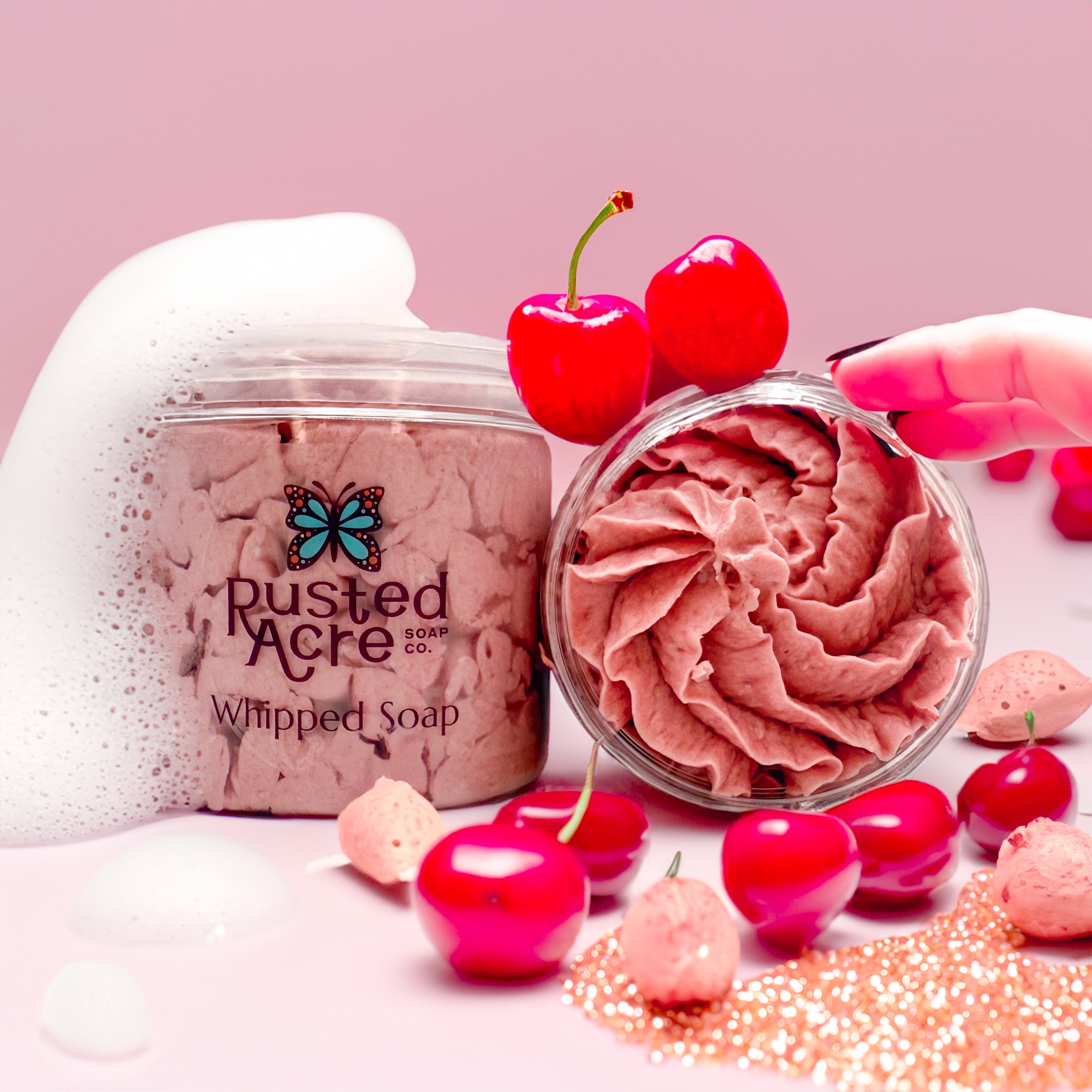 Two jars of Rusted Acre Soap Company’s cherry almond whipped soap front and top view in a lifestyle setting. 