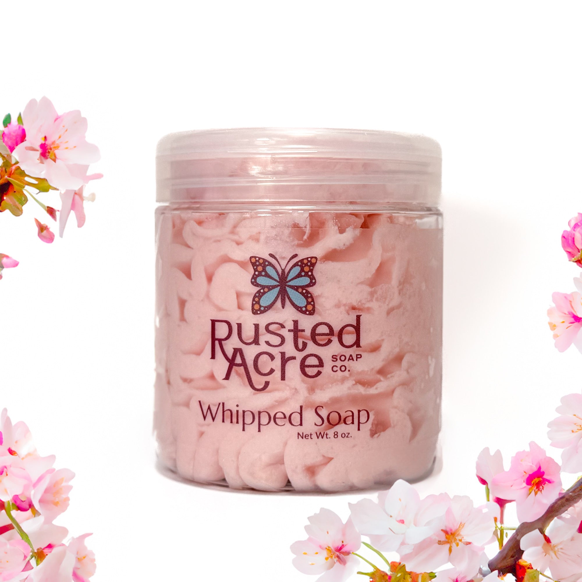 Jar of Rusted Acre Soap Company's vegan cherry blossom whipped soap. Pink  soap in a reusable plastic jar in a lifestyle setting. 