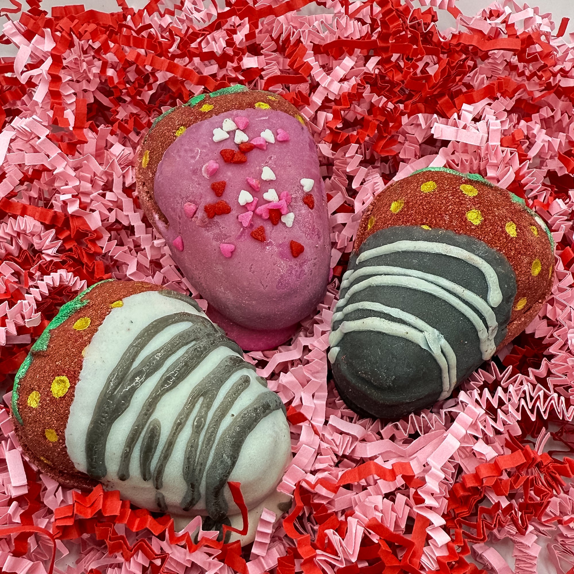 Three chocolate covered strawberry bath bombs sitting in pink and red crinkle paper.
Handmade and hand dipped 