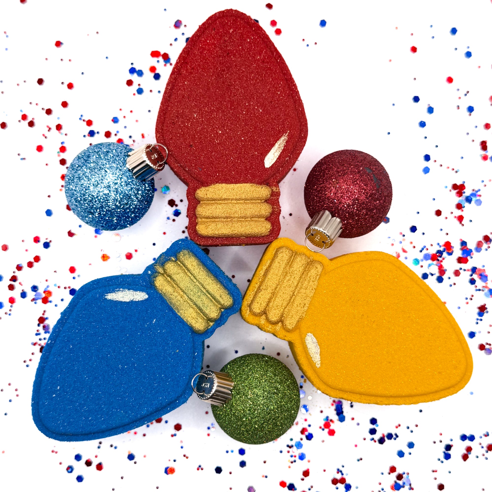 Colorful light bulb shaped bath bombs made by Rusted Acre Soap Co with decorative ornaments on a confetti background.