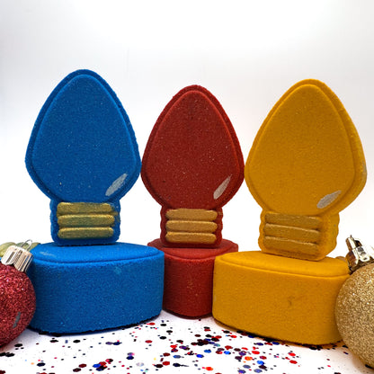Colorful light bulb shaped Christmas bath bombs on a white background with confetti.