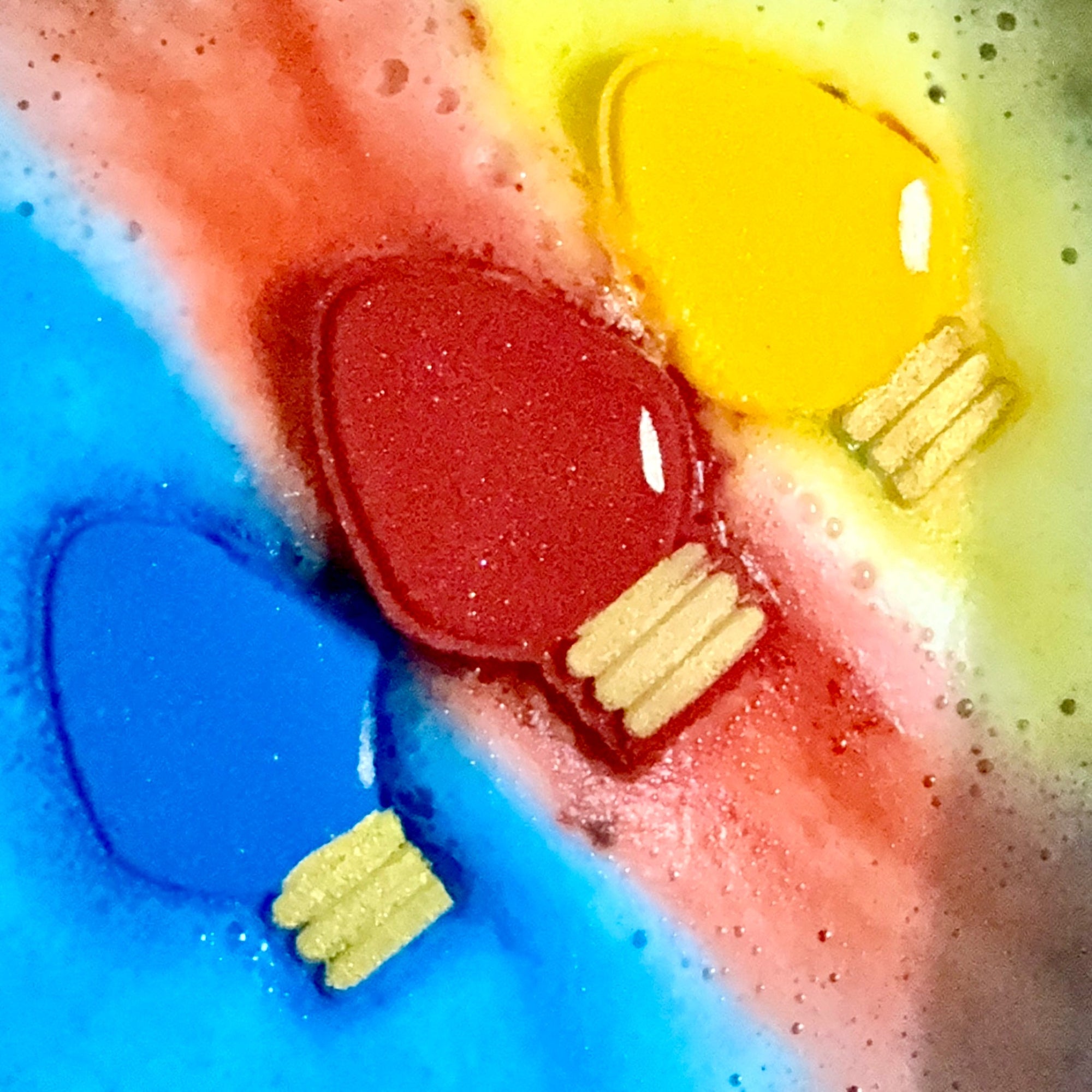 Colorful Christmas lights bath bombs with red , yellow, and blue colors in a water fizzing. 