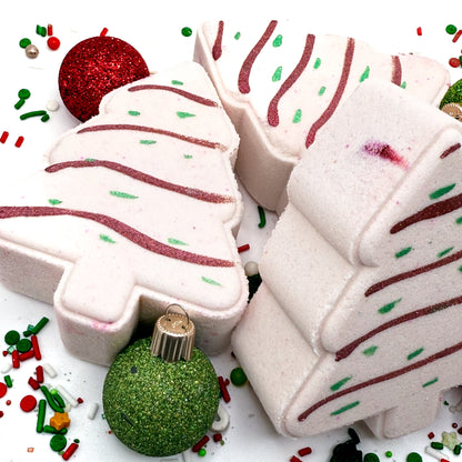 Decorative bath bombs shaped like Christmas trees with festive sprinkles on a white background