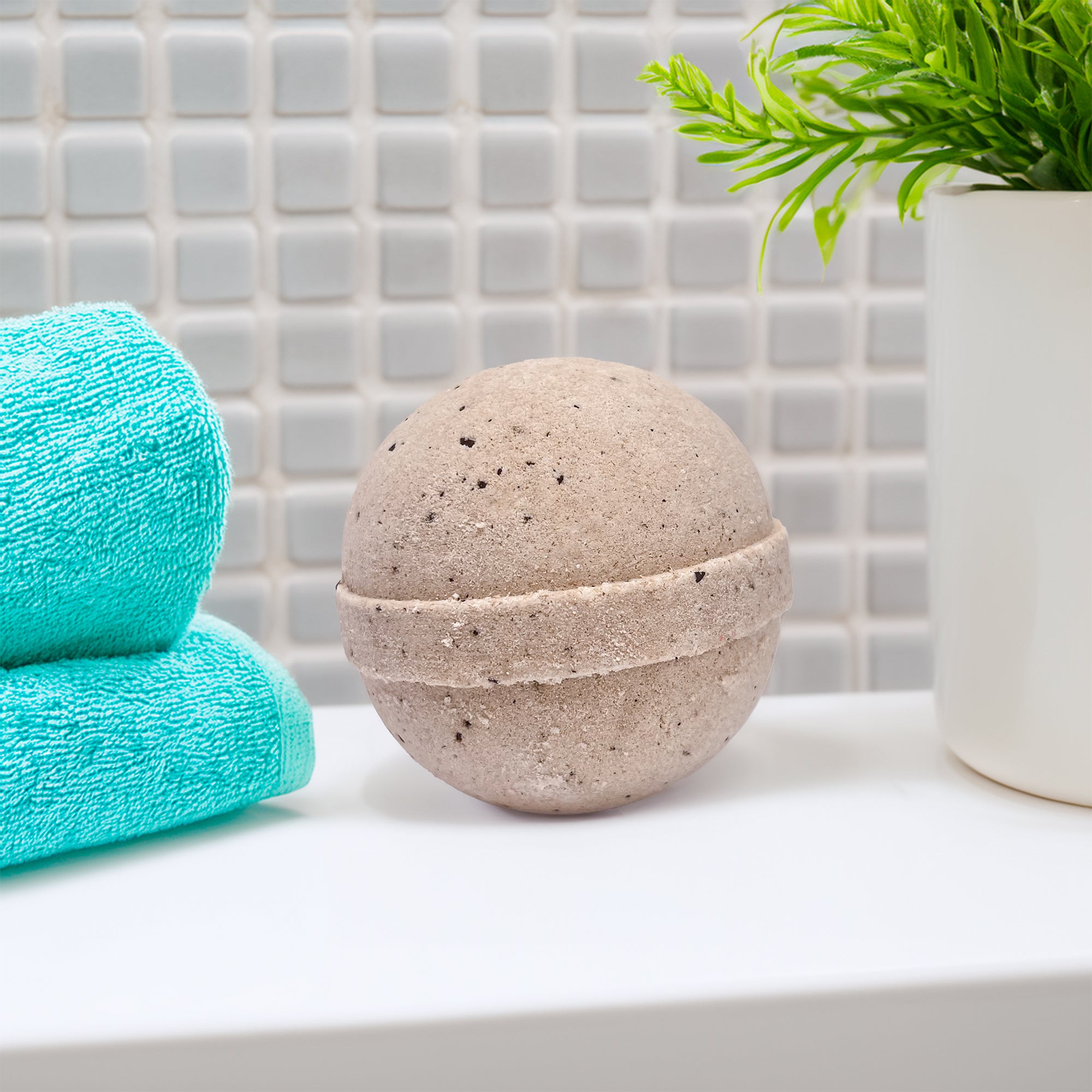 Rusted Acre Soap Company's coffee bath bomb in a bathroom on the counter by a folded washcloth.