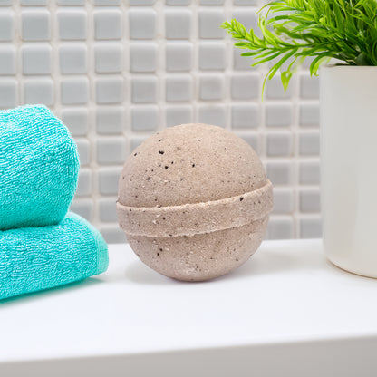 Rusted Acre Soap Company's coffee bath bomb in a bathroom on the counter by a folded washcloth.