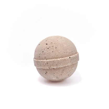 One round coffee bath bomb cream in color with coffee grounds sprinkled in.