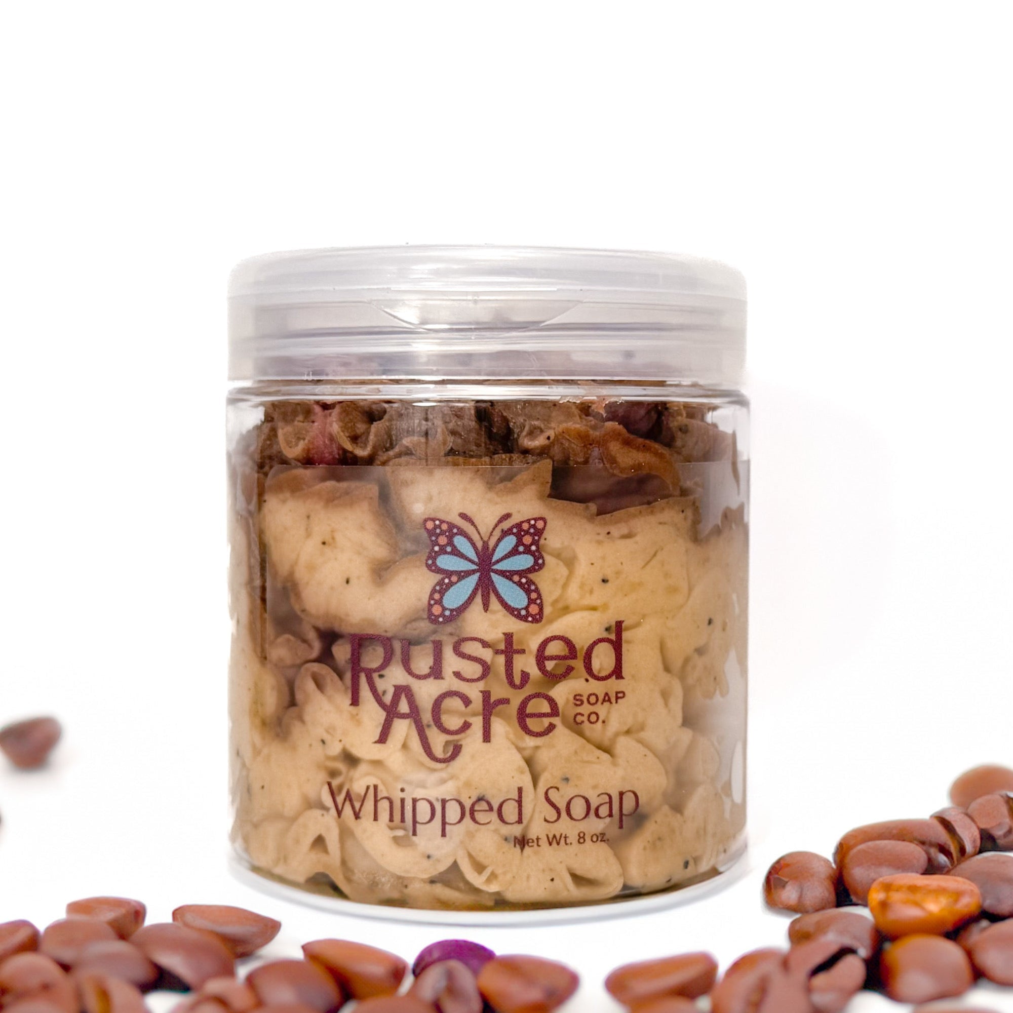 Jar of Rusted Acre Soap Company's vegan coffee whipped soap. Brown soap with coffee grounds  in a reusable plastic jar in a lifestyle setting. 