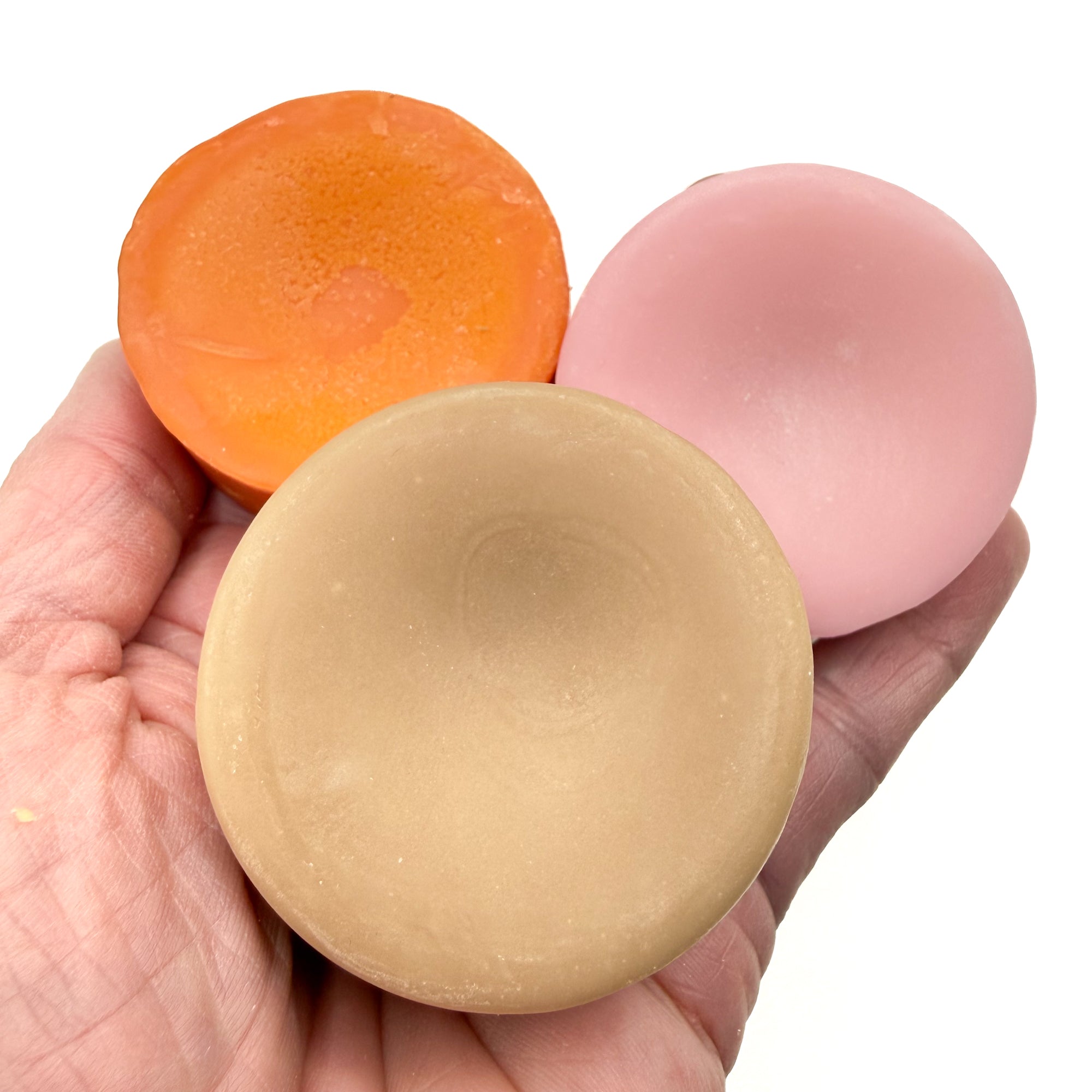 Three colorful conditioner bars  held in a hand against a white background