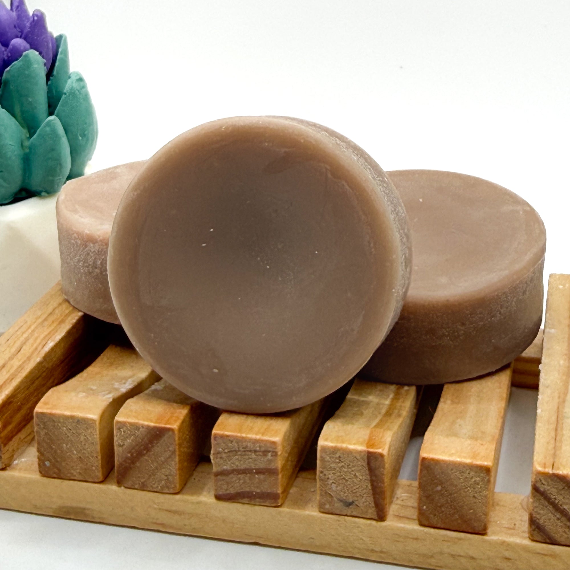 Three brown rice protein conditioner bars on a wooden soap dish with a white background.