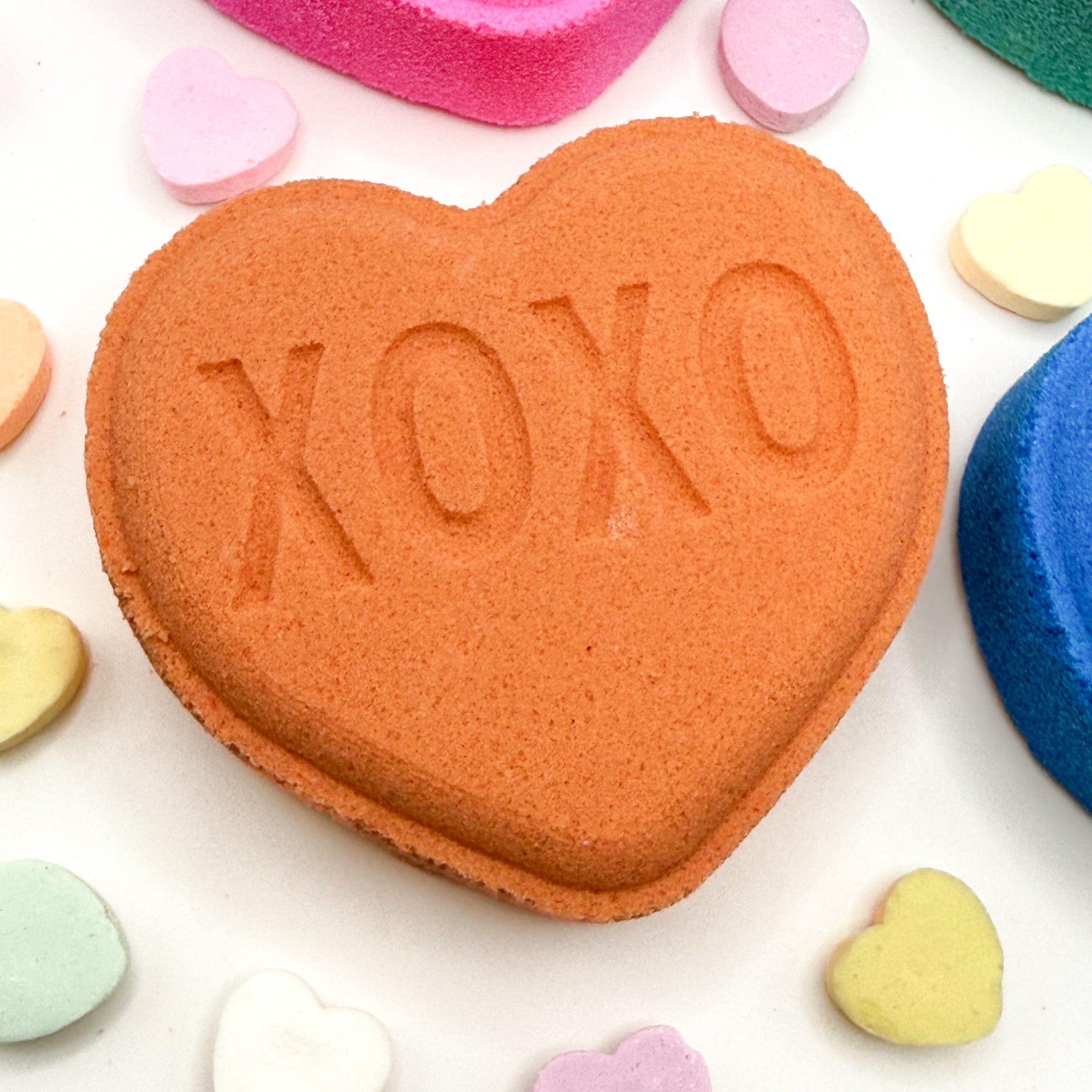 Heart shaped bath bomb with 'XOXO' embossed on a white background