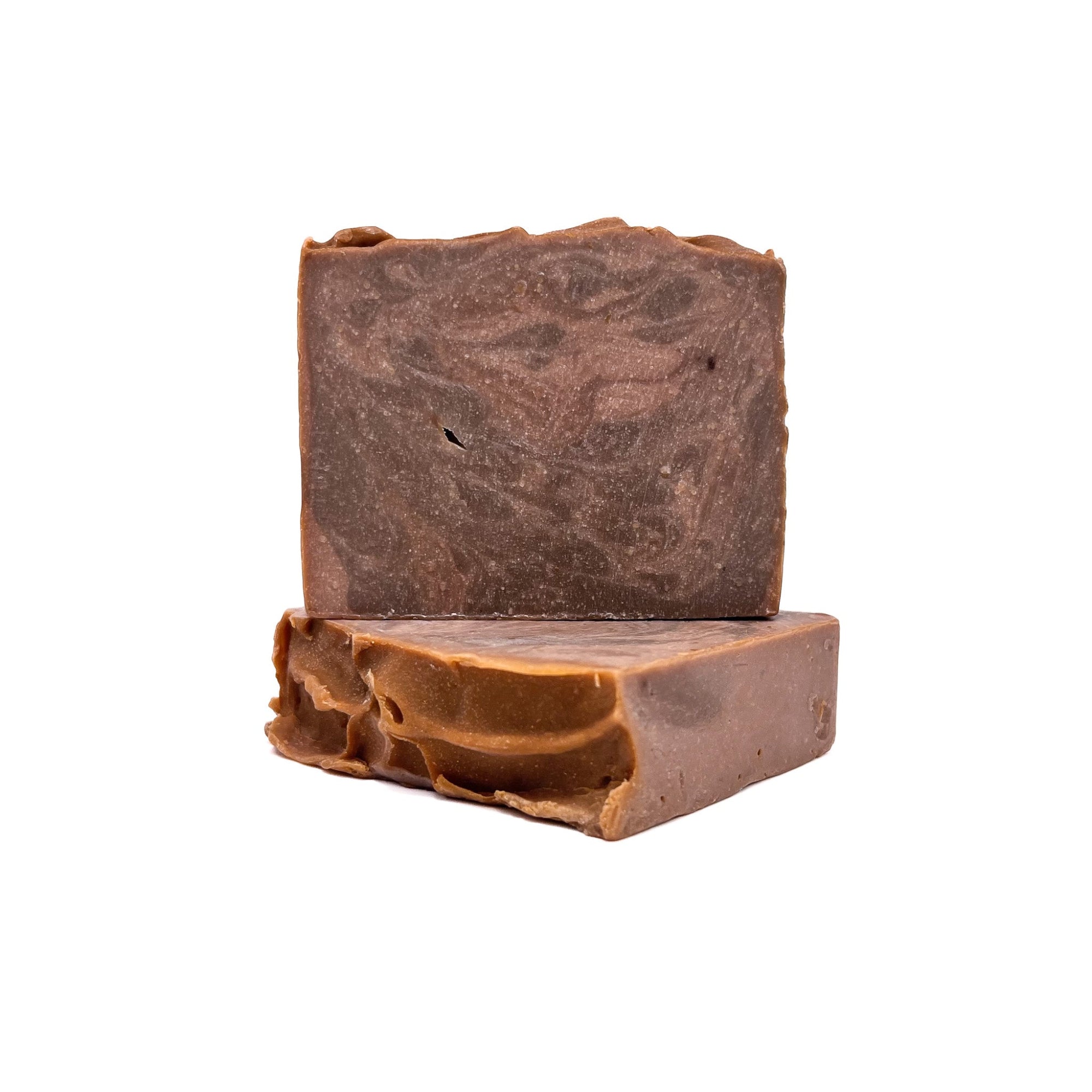 Two bars of Rusted Acre Soap Company's Cowboy handmade soap. Swirled dark brown and light brown like leather! One upright and one flat to show texture.
