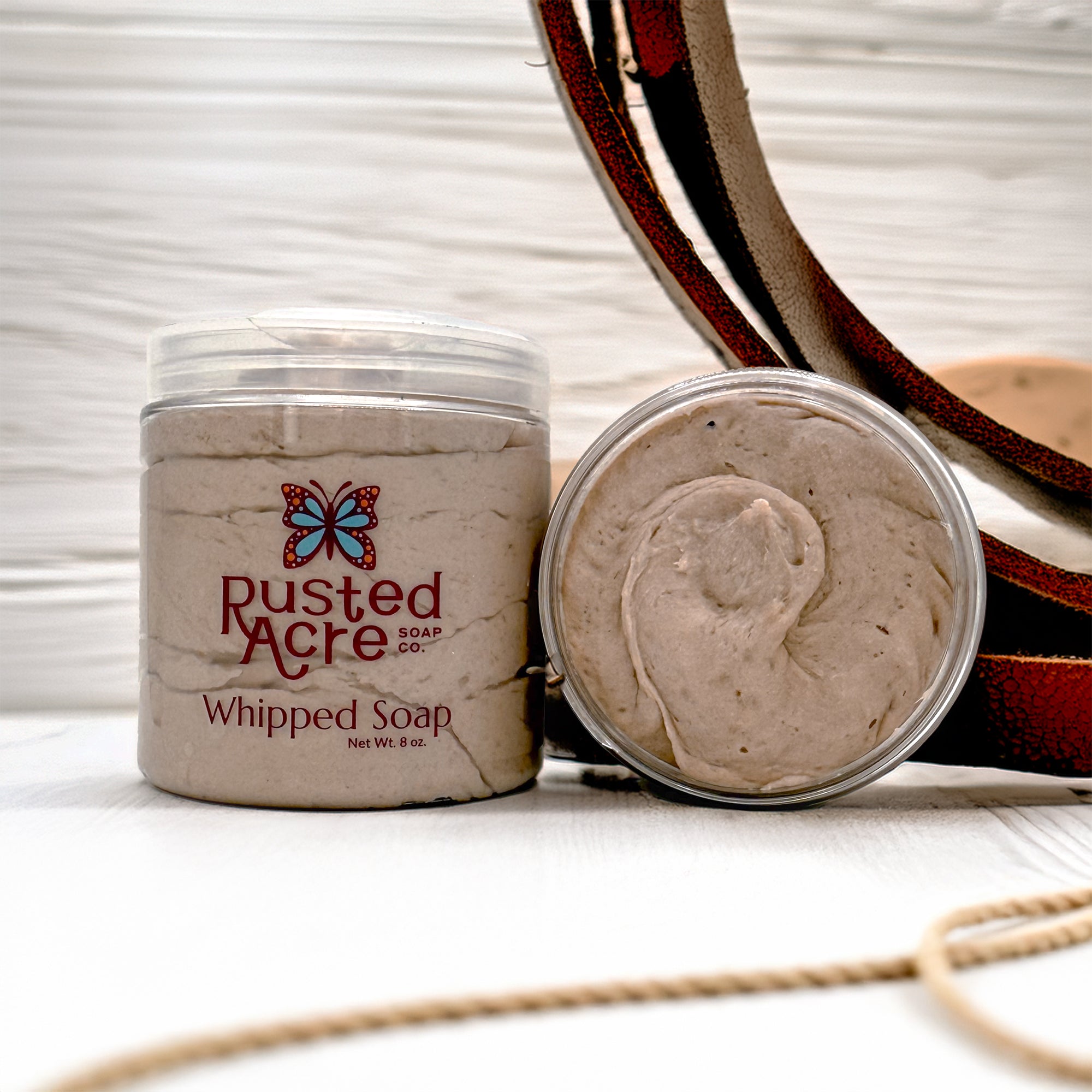 Two jars of Rusted Acre Soap Company's cowboy whipped soap in a lifestyle image.