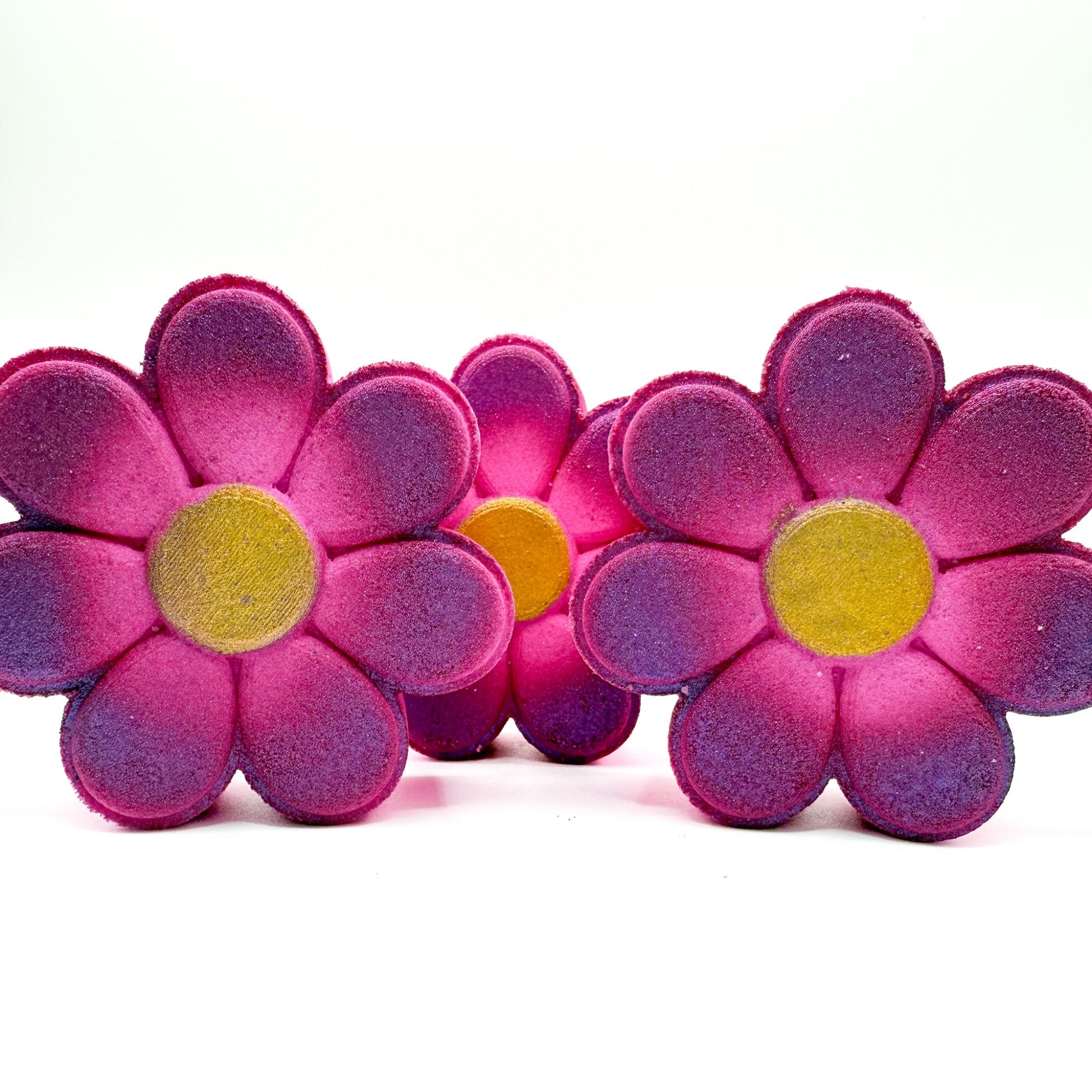 Three hand painted daisy bath bombs made by Rusted Acre Soap Company. Pink with gold center. 