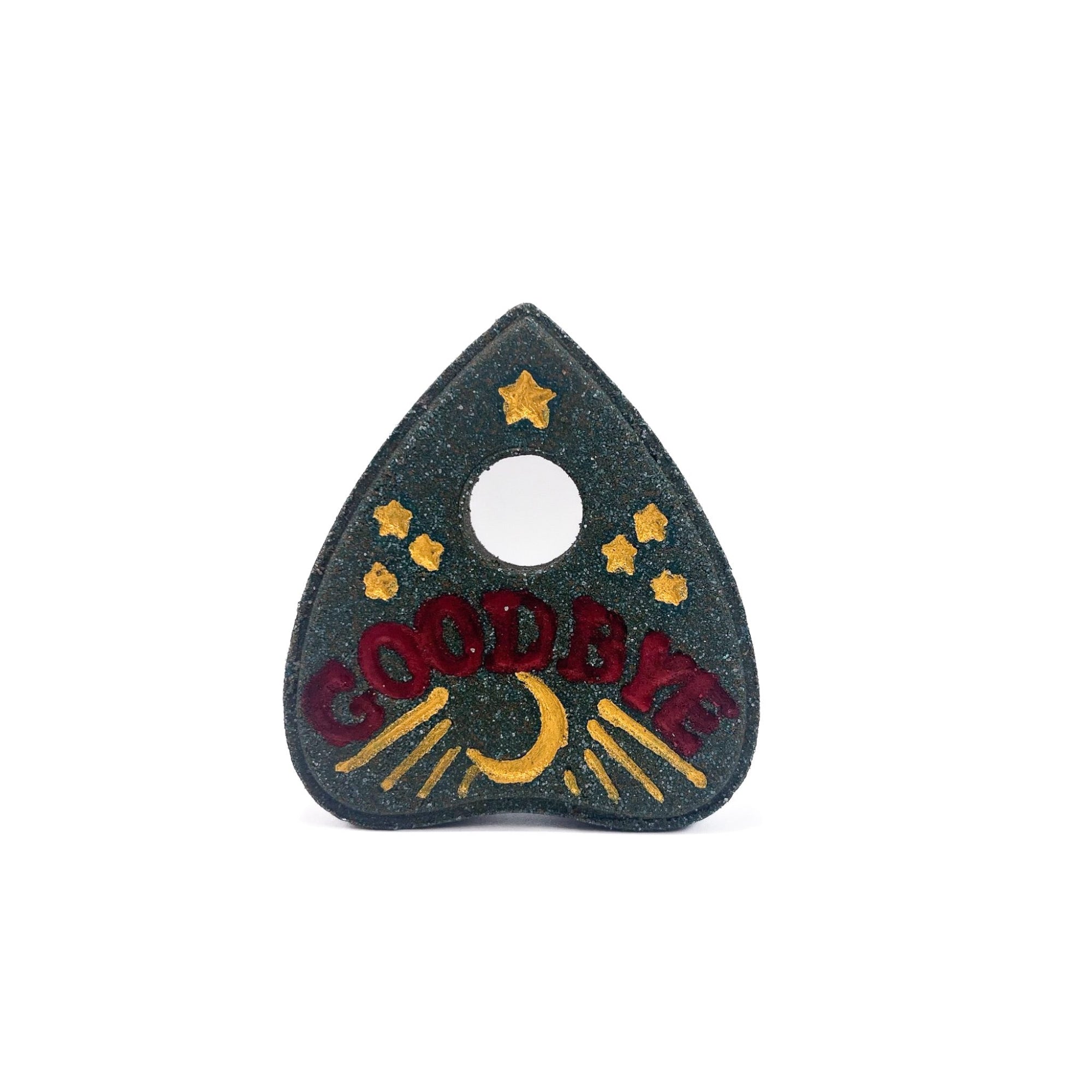 A black planchette bath bomb. Hand-painted stars, moon, moonbeams, gold and "GOODBYE" in red.