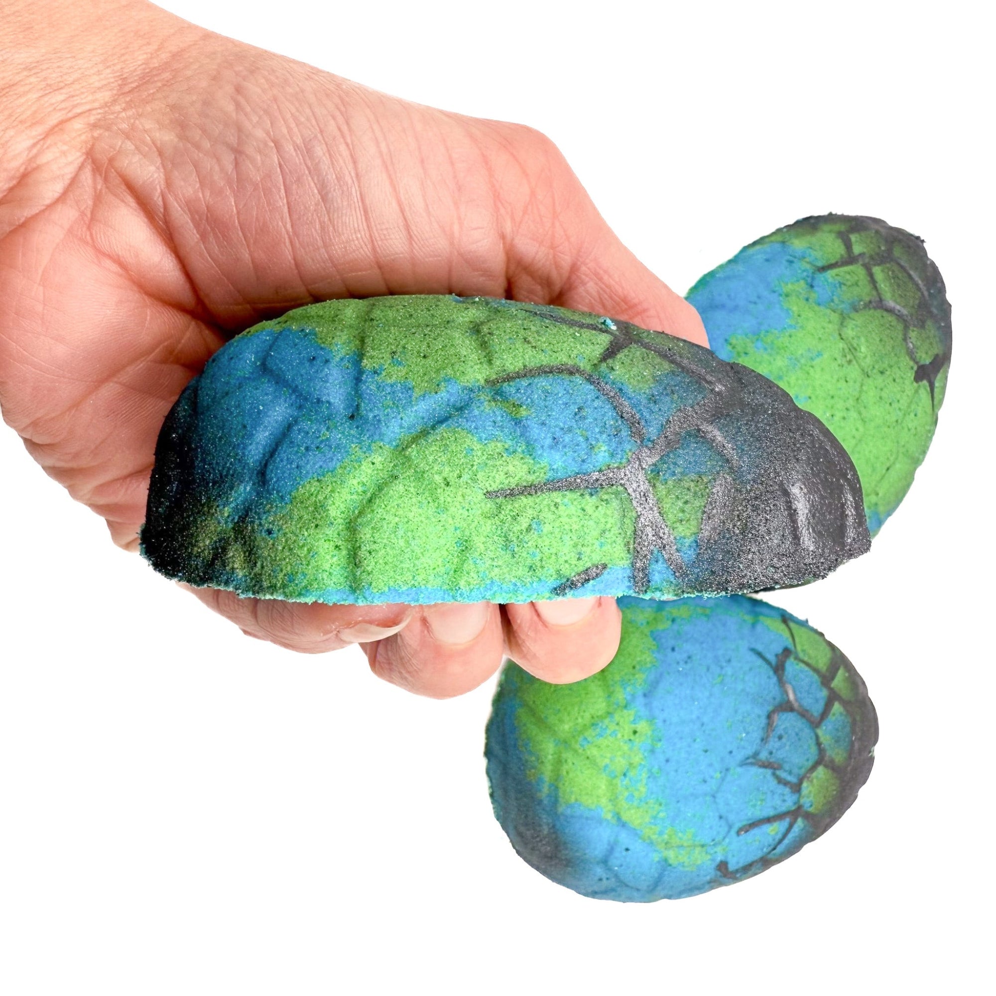 Side view of a dinosaur Egg bath bomb in hand from Rusted Are Soap Company 