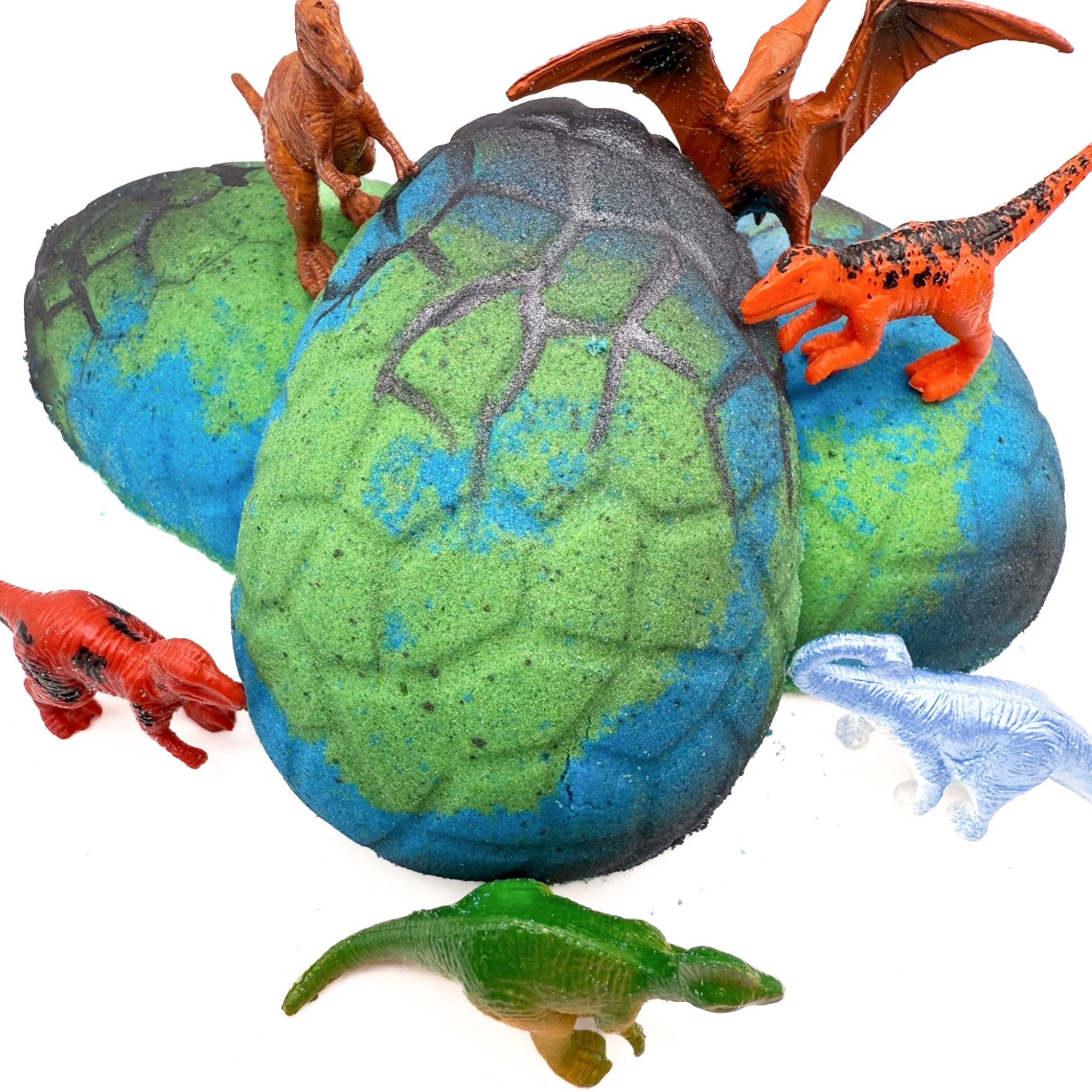 Dino Egg bath bomb for kids made by Rusted Acre Soap Company. Three blue and green eggs in picture with dinosaur toys.