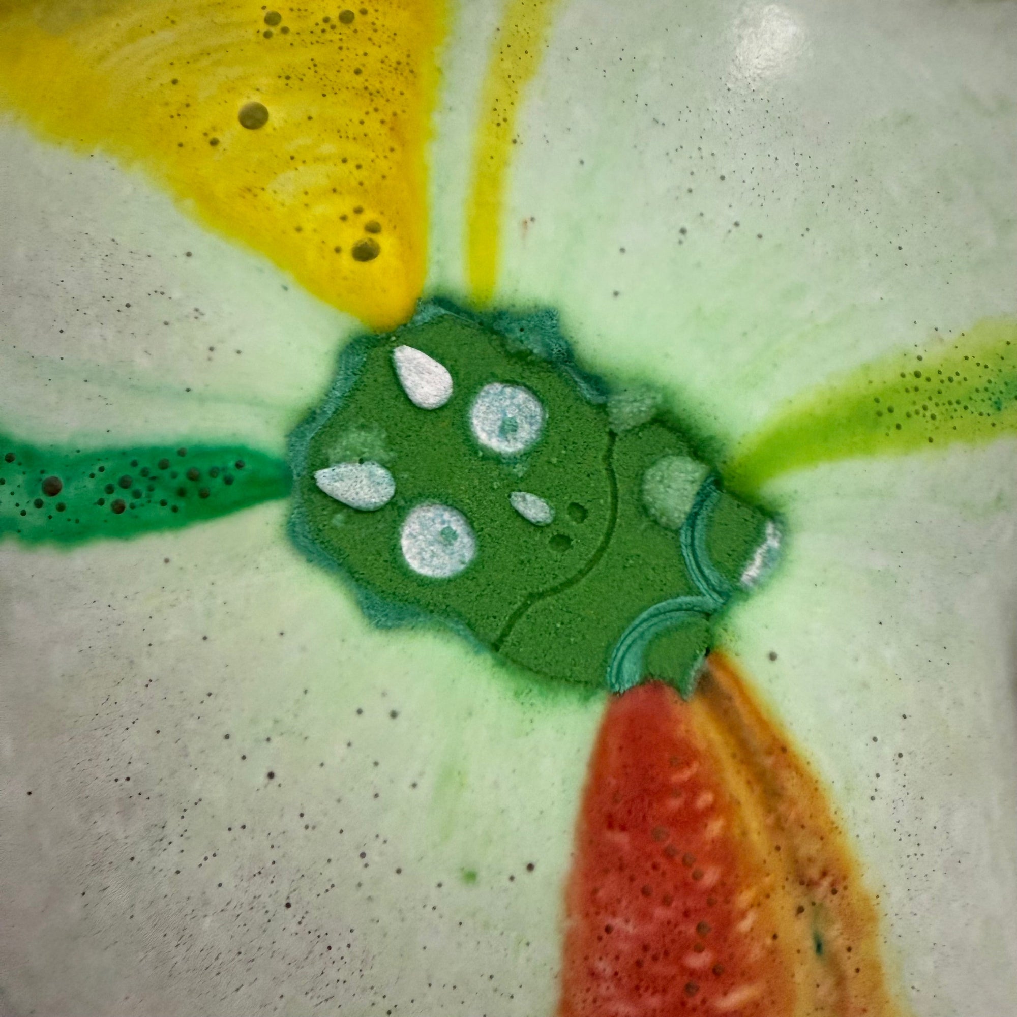 Dinosaur bath bomb in the water showing the surprise colors inside. Hand made and hand painted by Rusted Acre Soap Co.