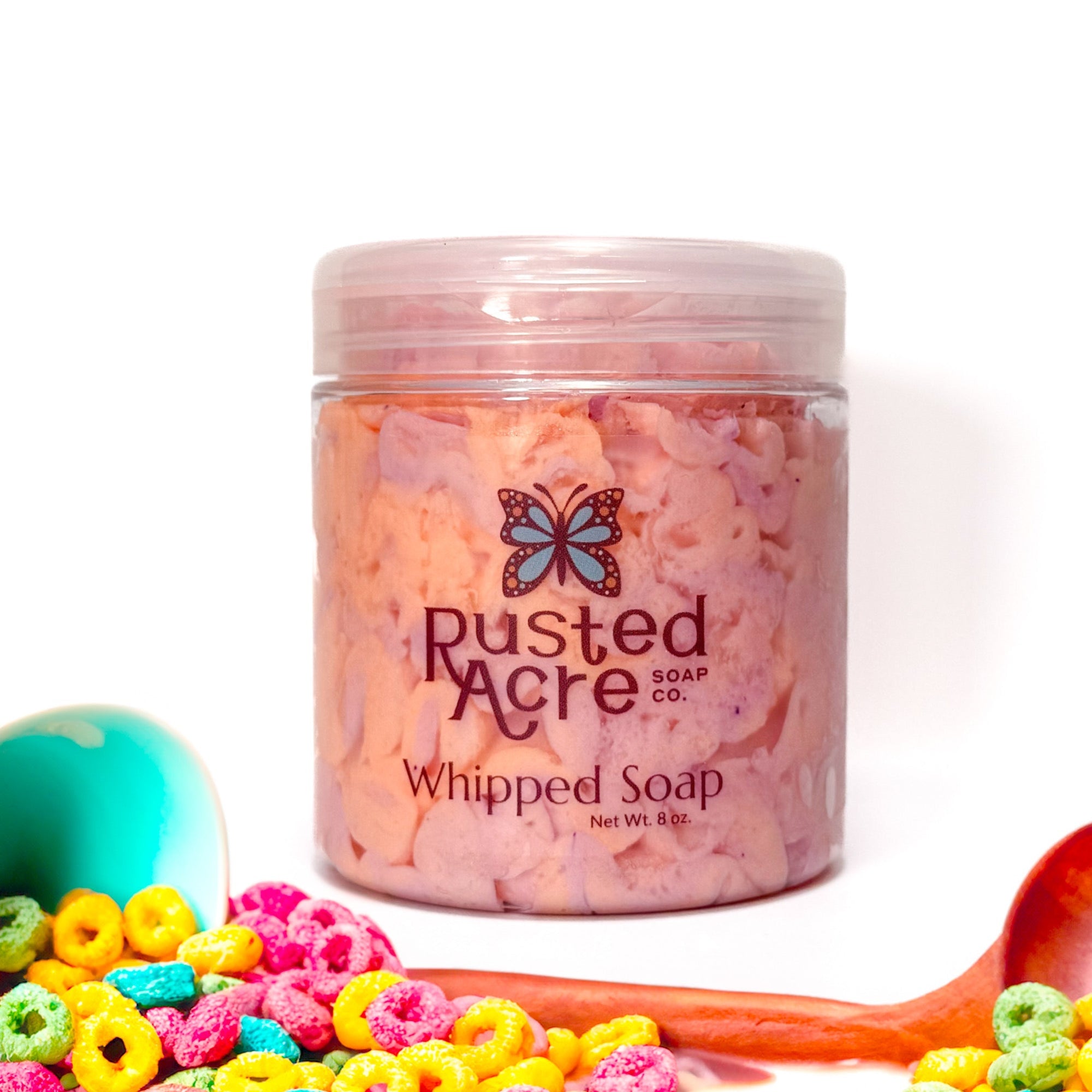 Jar of Rusted Acre Soap Company's vegan fruity cereal whipped soap. Pink and Orange soap in a reusable plastic jar in a lifestyle setting. 