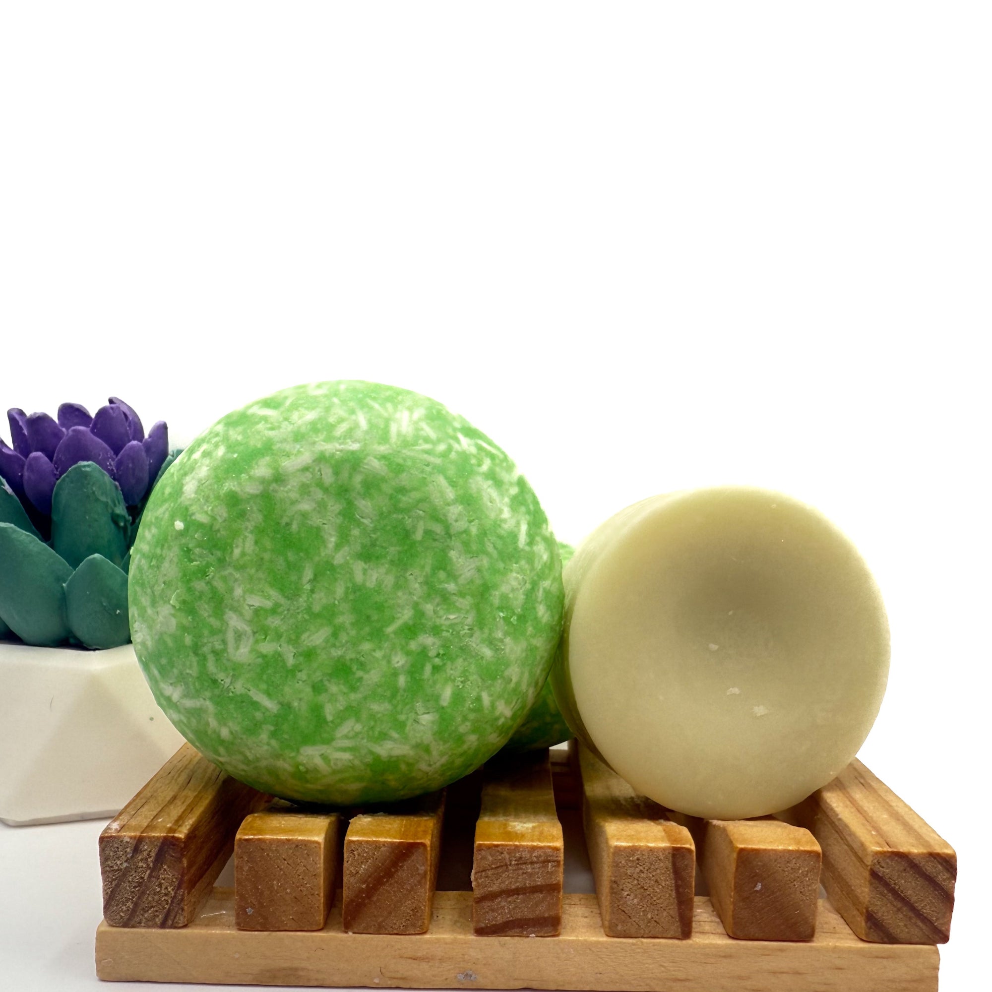Green coconut lime cooler zero waste Shampoo and Conditioner bar on a wood soap dish with a white background standing on side.