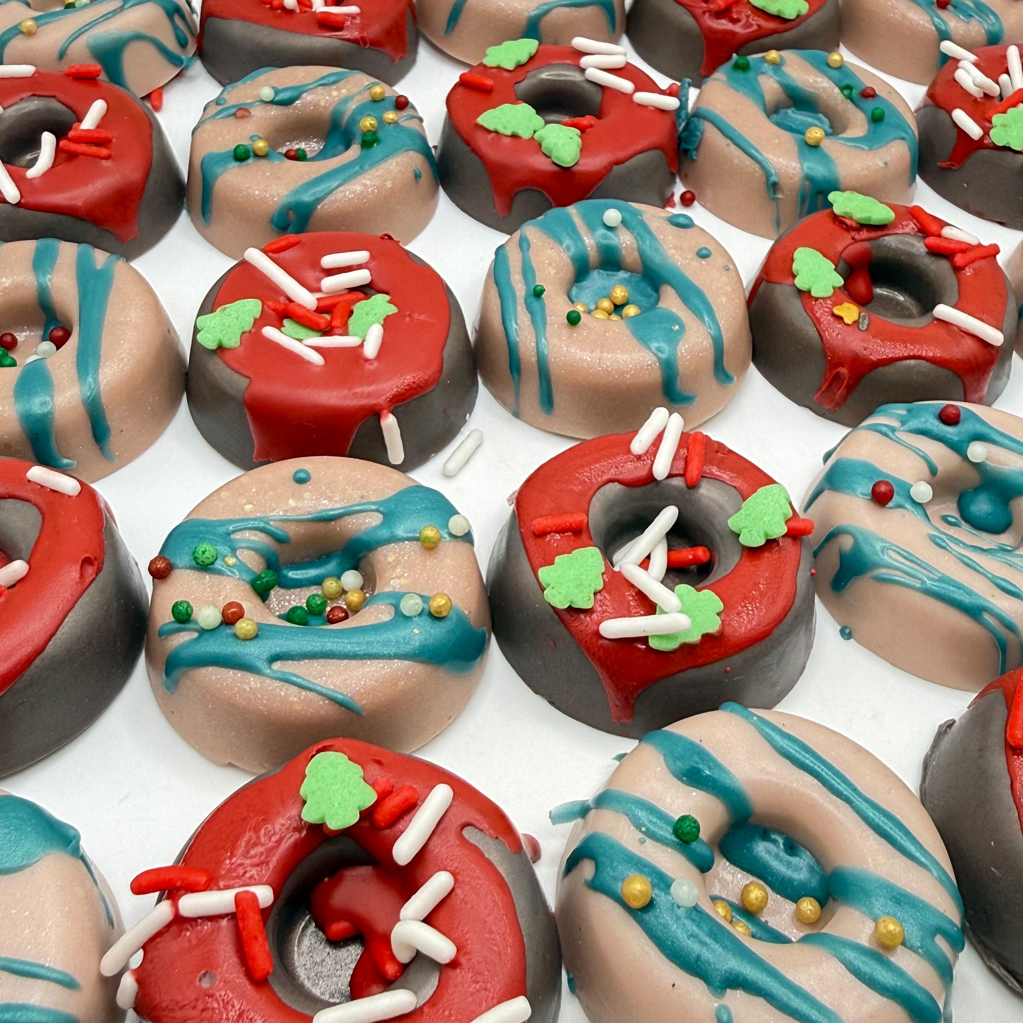 Assorted mini donut soap handmade by Rusted Acre Soap Co with red and green icing holiday sprinkles on a white background.